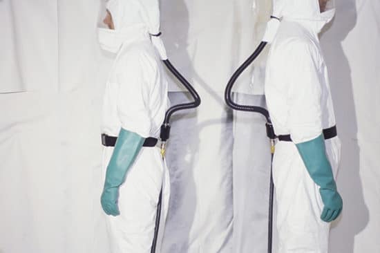 Two men wearing protective clean suits, or hazmat suits and breathing apparatus.